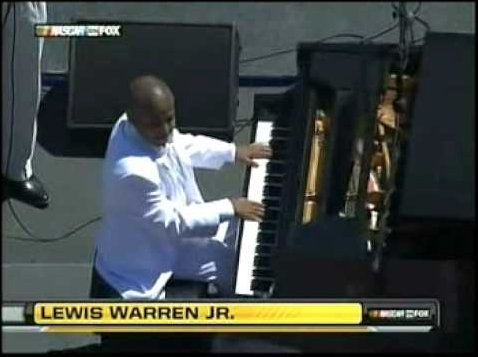 Lewis Warren Jr. plays piano while wearing a white suit.