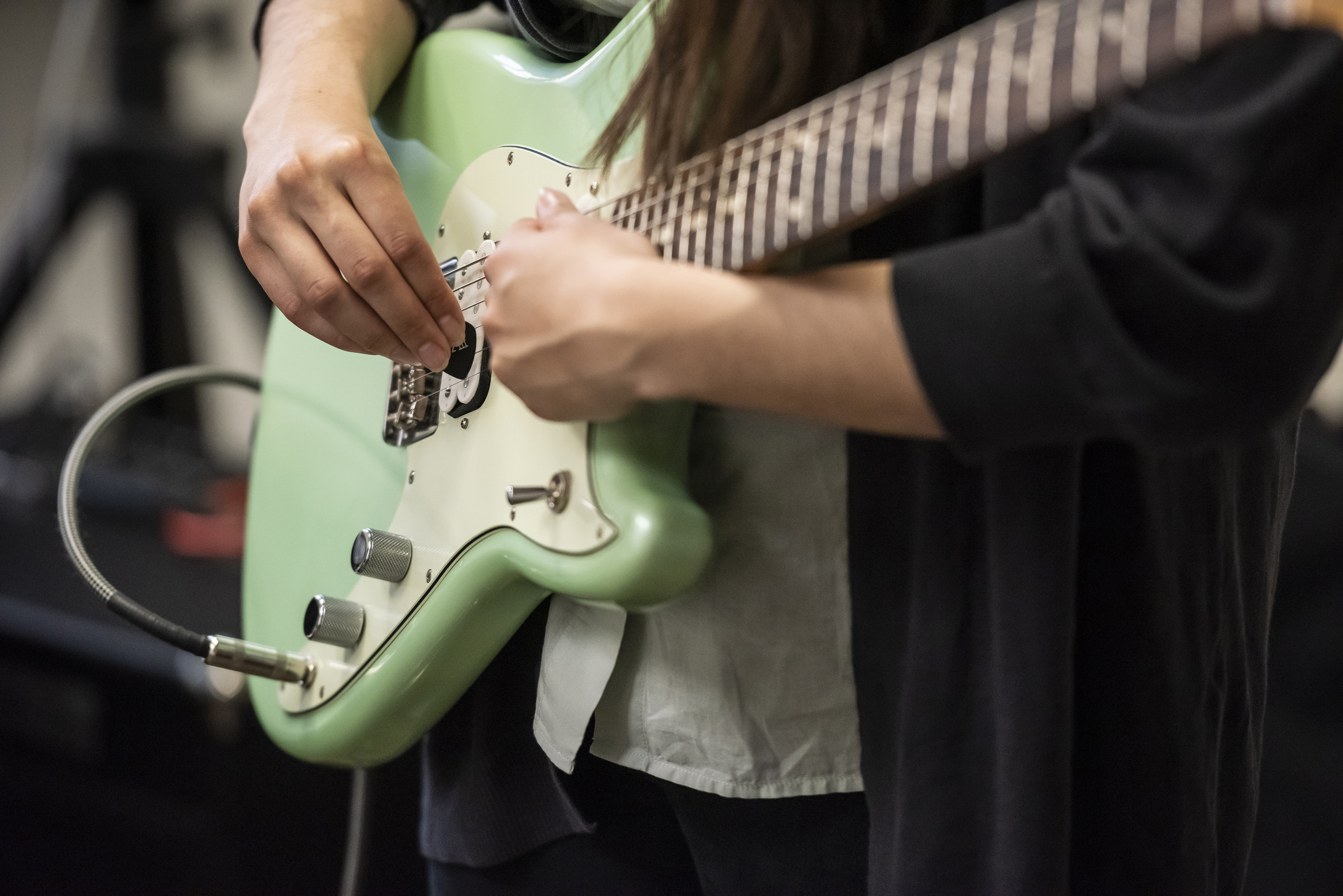 Close up of Magdalena's mint green electric guitar