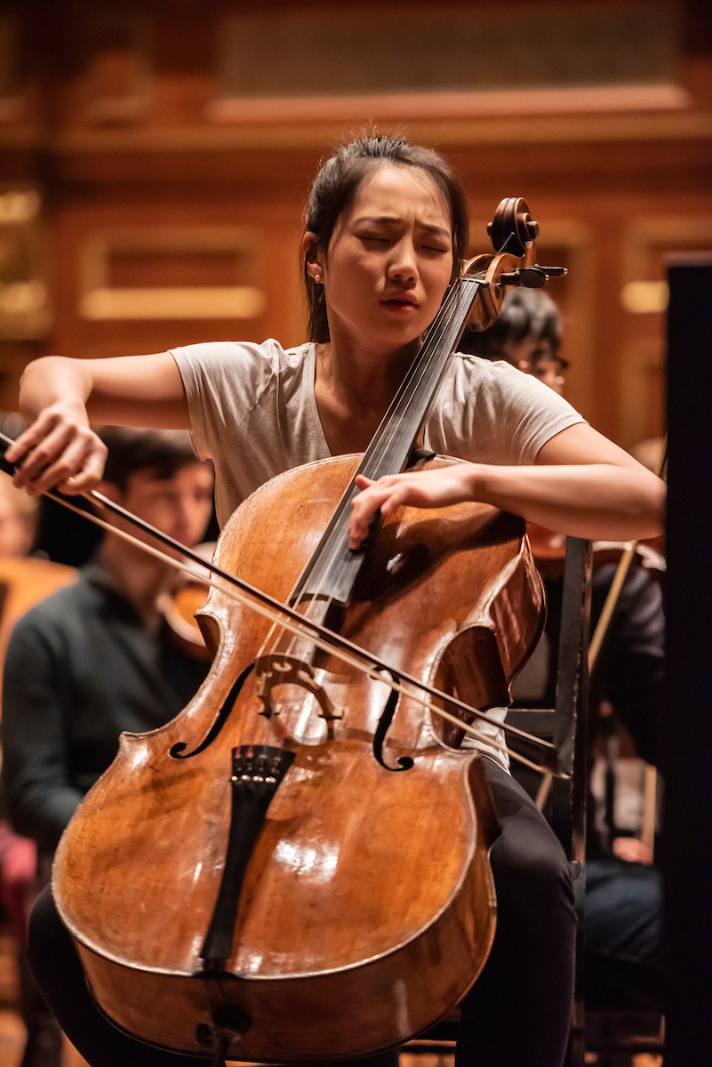 Claire Deokyong Kim plays the cello with an expression of emotion on her face.