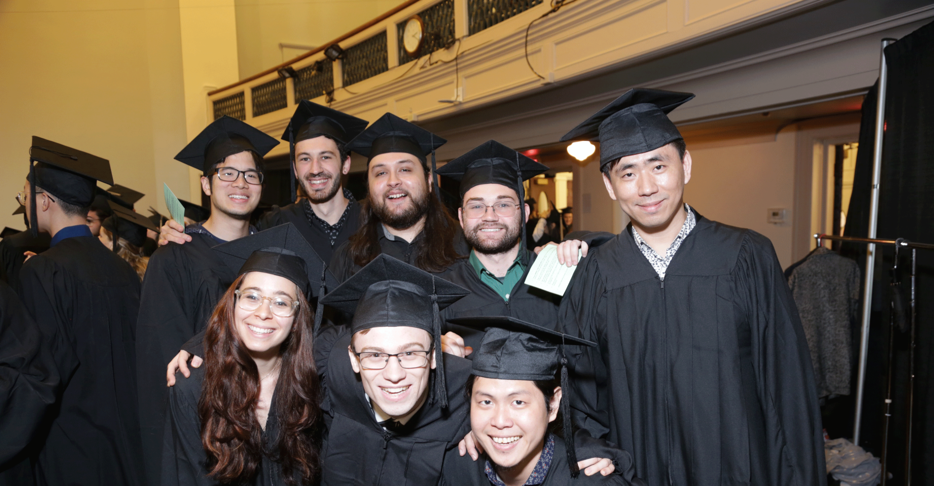 Eight smiling graduates wearing caps and gowns