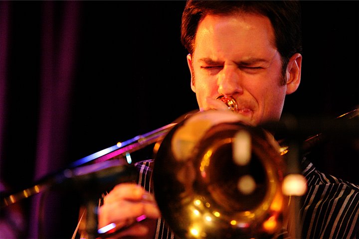 Joel Yennior plays trombone with feeling under stage lighting