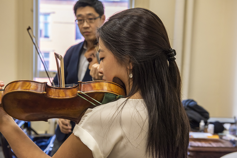 Close up view of Abigail Hong violin playing with Soovin Kim in background