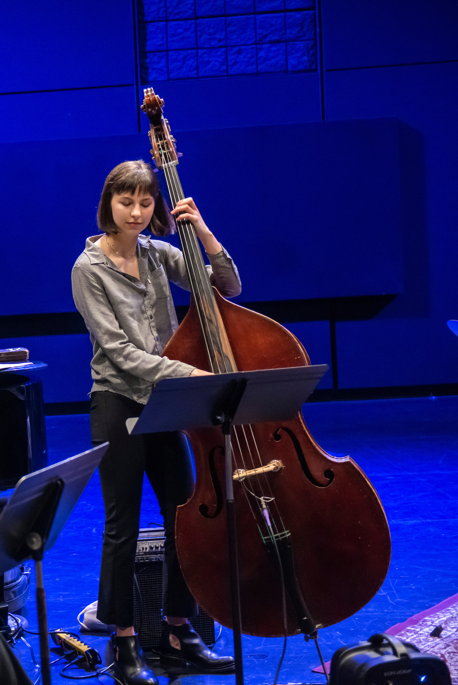 A bassist closes her eyes and smiles while playing in a jazz small ensemble.