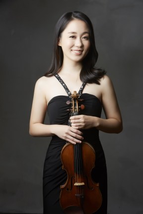Eunae Koh smiles while holding her violin.