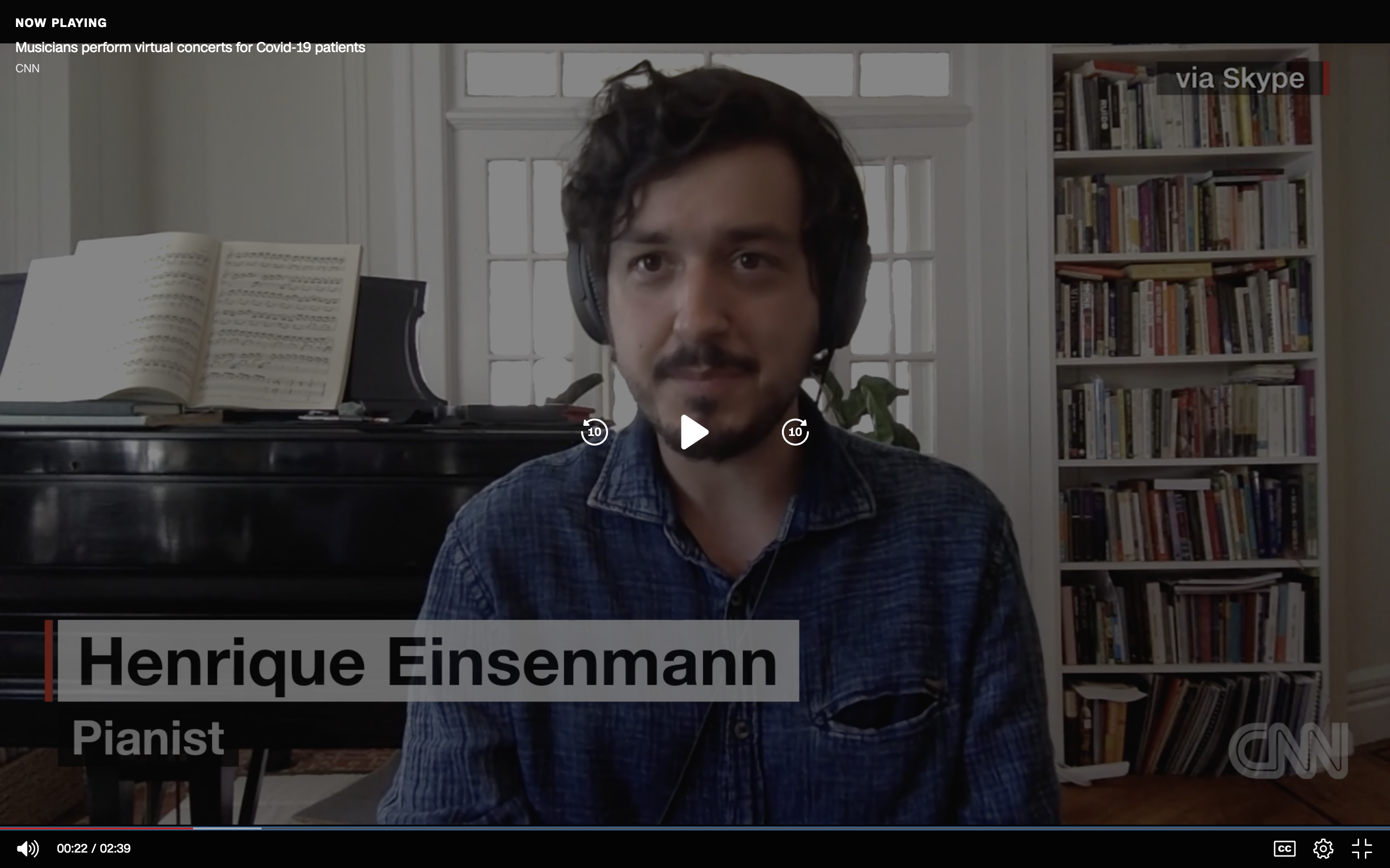 Henrique Eisenmann, pianist, speaks to CNN from his home, with a piano and bookshelf in the background
