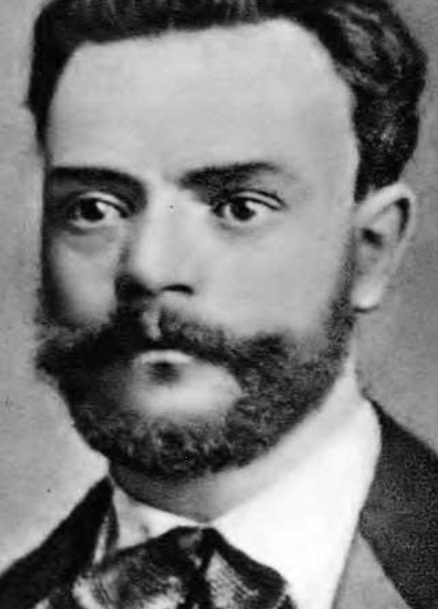 Black and white portrait of Antonin Dvorak. He is wearing an ascot and suit jacket and a mutton-chops style moustache and beard.