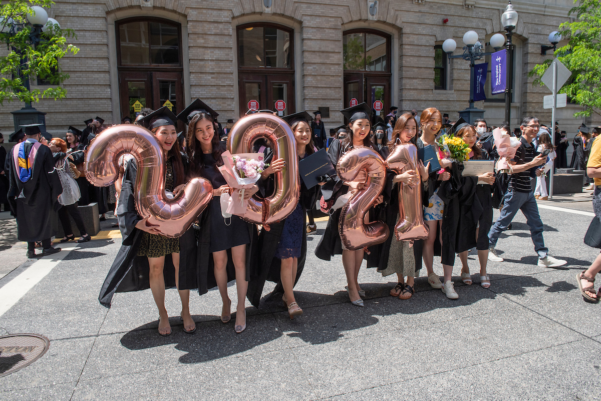 A group of graduates holds balloons that spell out "2021"