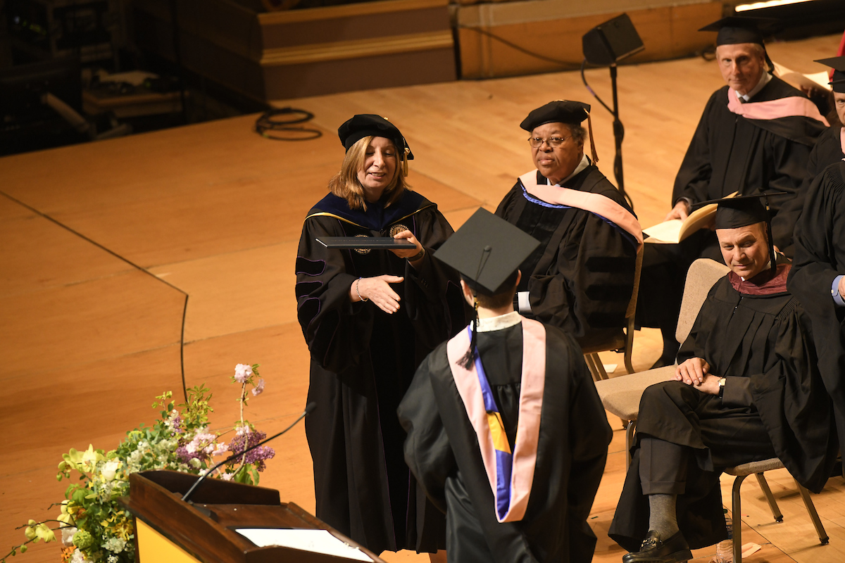 President Andrea Kalyn extends her hand to a graduate