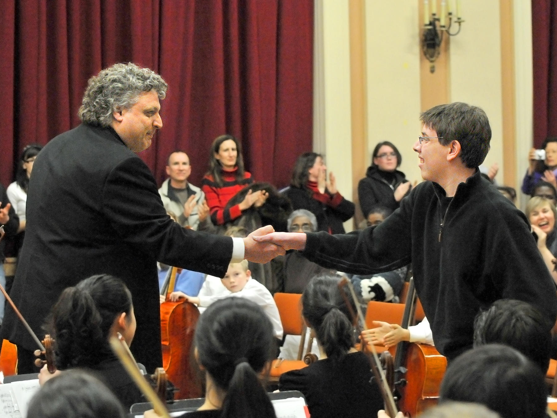 Steven Karidoyanes shakes hands with a young composer