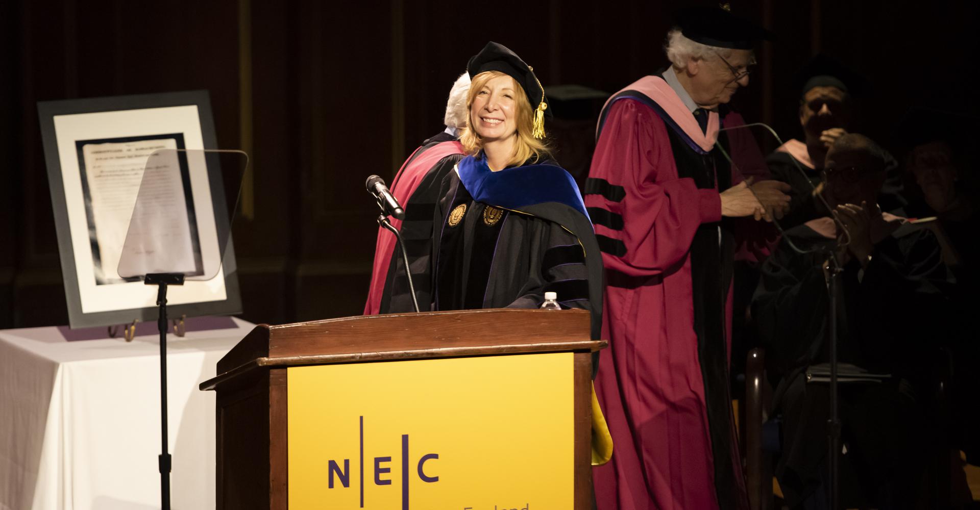 President Andrea Kalyn smiles at the podium on the stage of Jordan Hall
