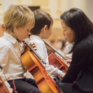 A Prep teacher helps a Suzuki cellist tune