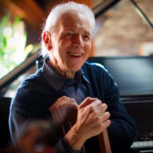 Pianist Russell Sherman smiles while seated at piano