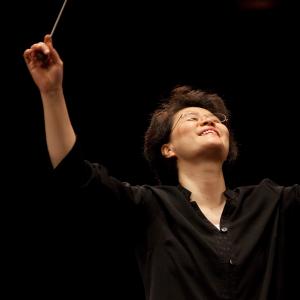 Mei-Ann Chen conducts, both hands raised over her head