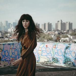 Composer Missy Mazzoli poses in front of graffiti and an urban skyline