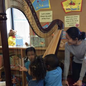 Sarah Yeoh-Wang with kids looking at the harp.