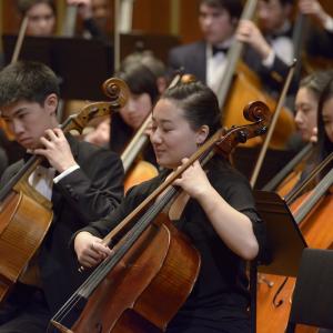 A cellist smiles and closes her eyes while playing with the Youth Philharmonic Orchestra.