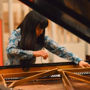 Satoko Fujii looks into the interior of a grand piano