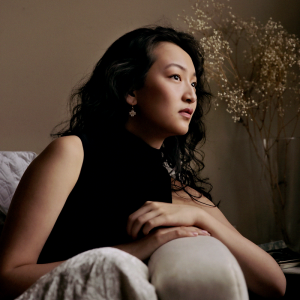Chelsea Guo reclines on a sofa, gazing to the right, past the camera.