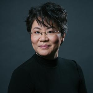 Mei Ann Chen portrait with dark background, smiling.