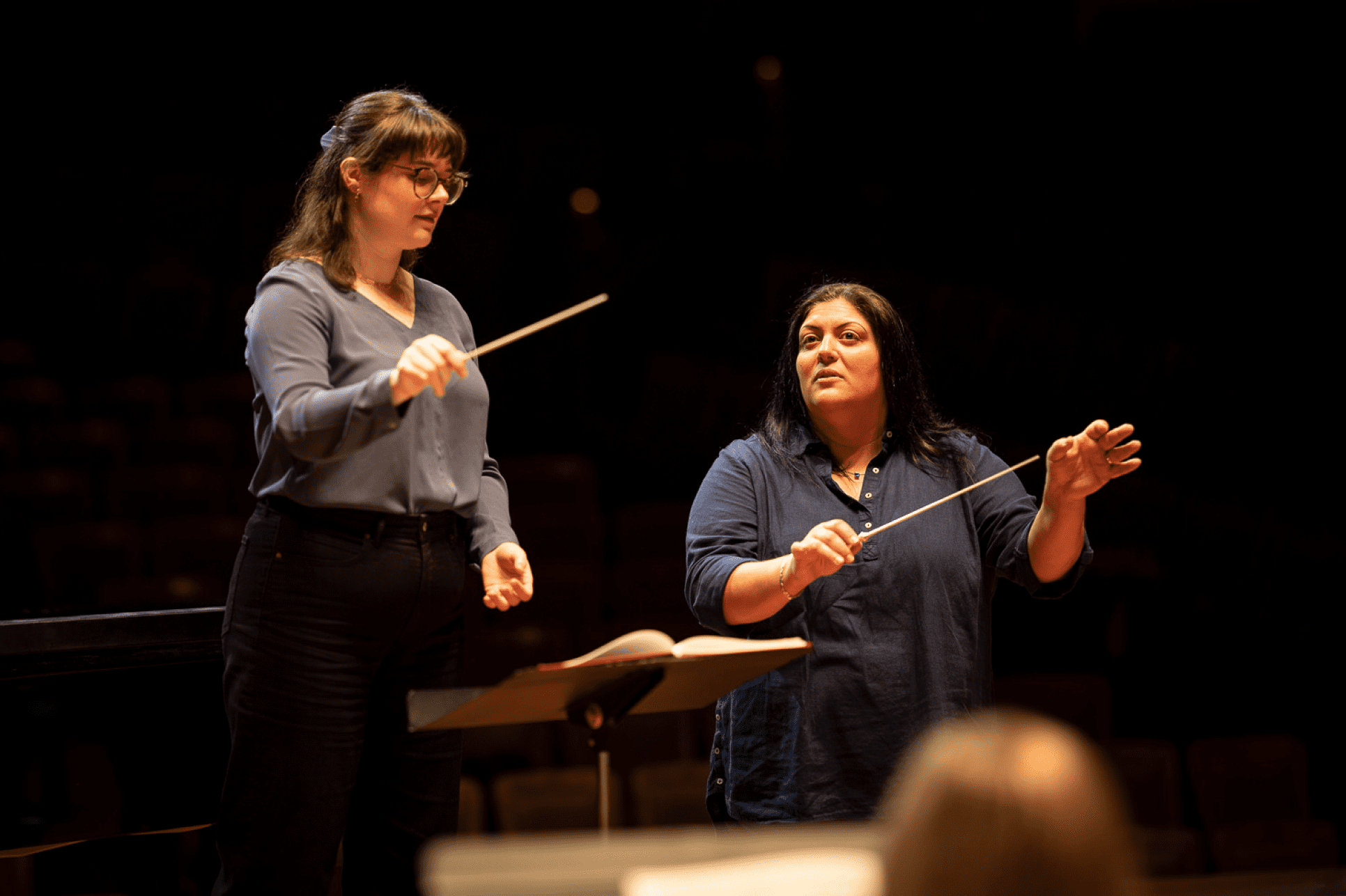 Erica Washburn coaching a conducting student on stage