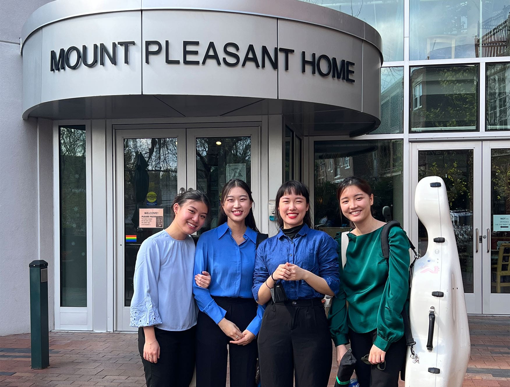 Four NEC students standing in front of an assisted living facility.