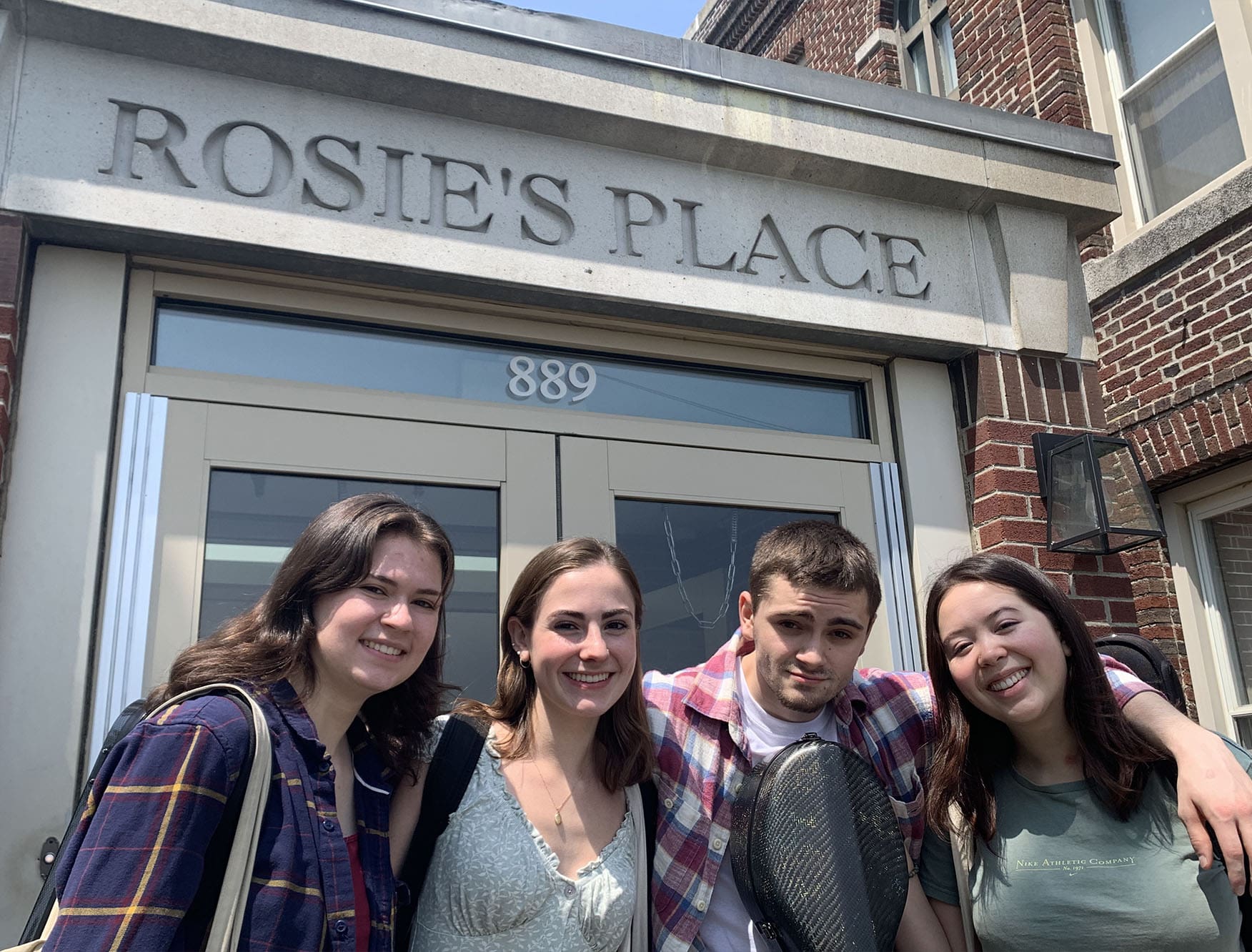 Four students smiling in front of the Rosie's Place building.