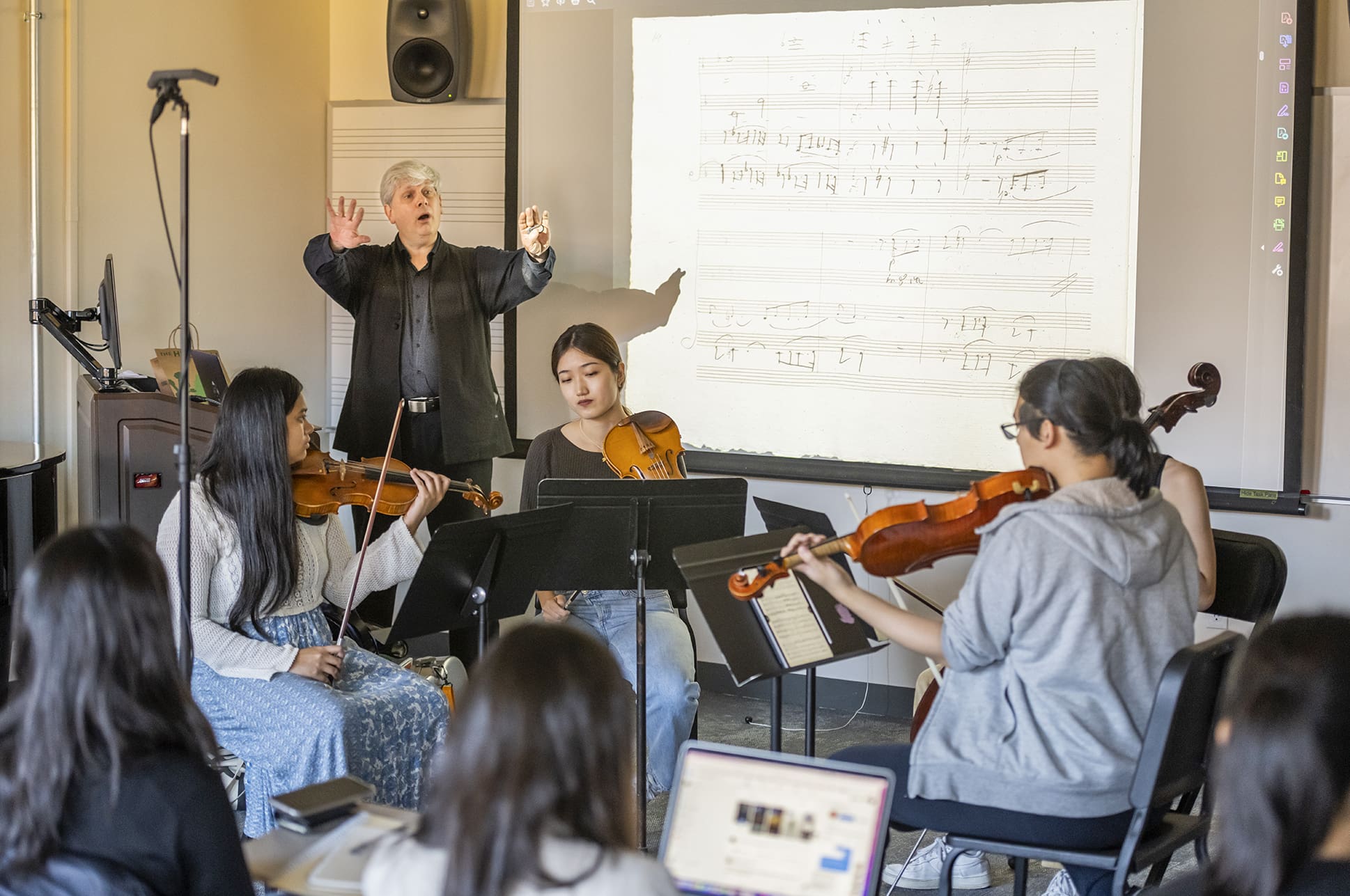 NEC faculty member Nick Kitchen teaching a class of students holding violins.
