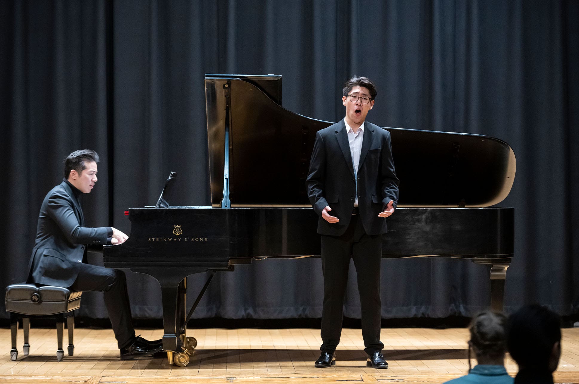 Student singing in front of a pianist on a stage.