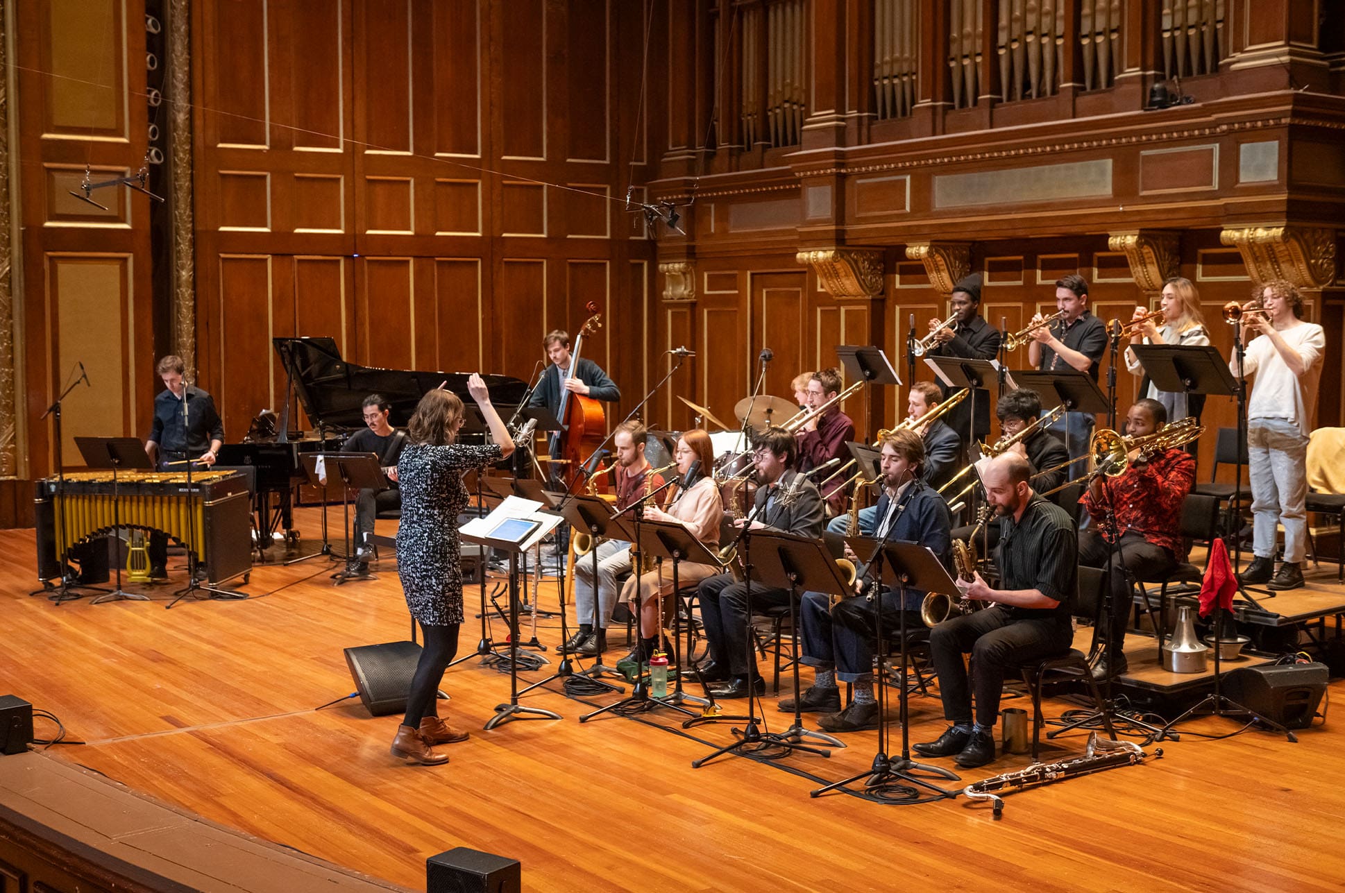 Person conducting an ensemble on the Jordan Hall stage.