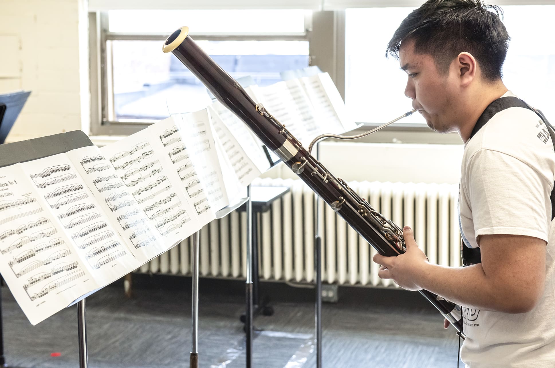 Student playing a bassoon and reading sheet music.
