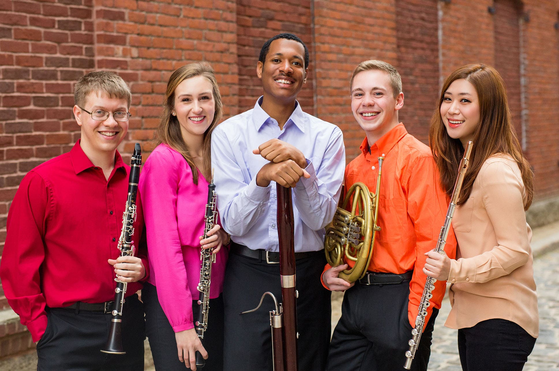 Five students standing together holding instruments.