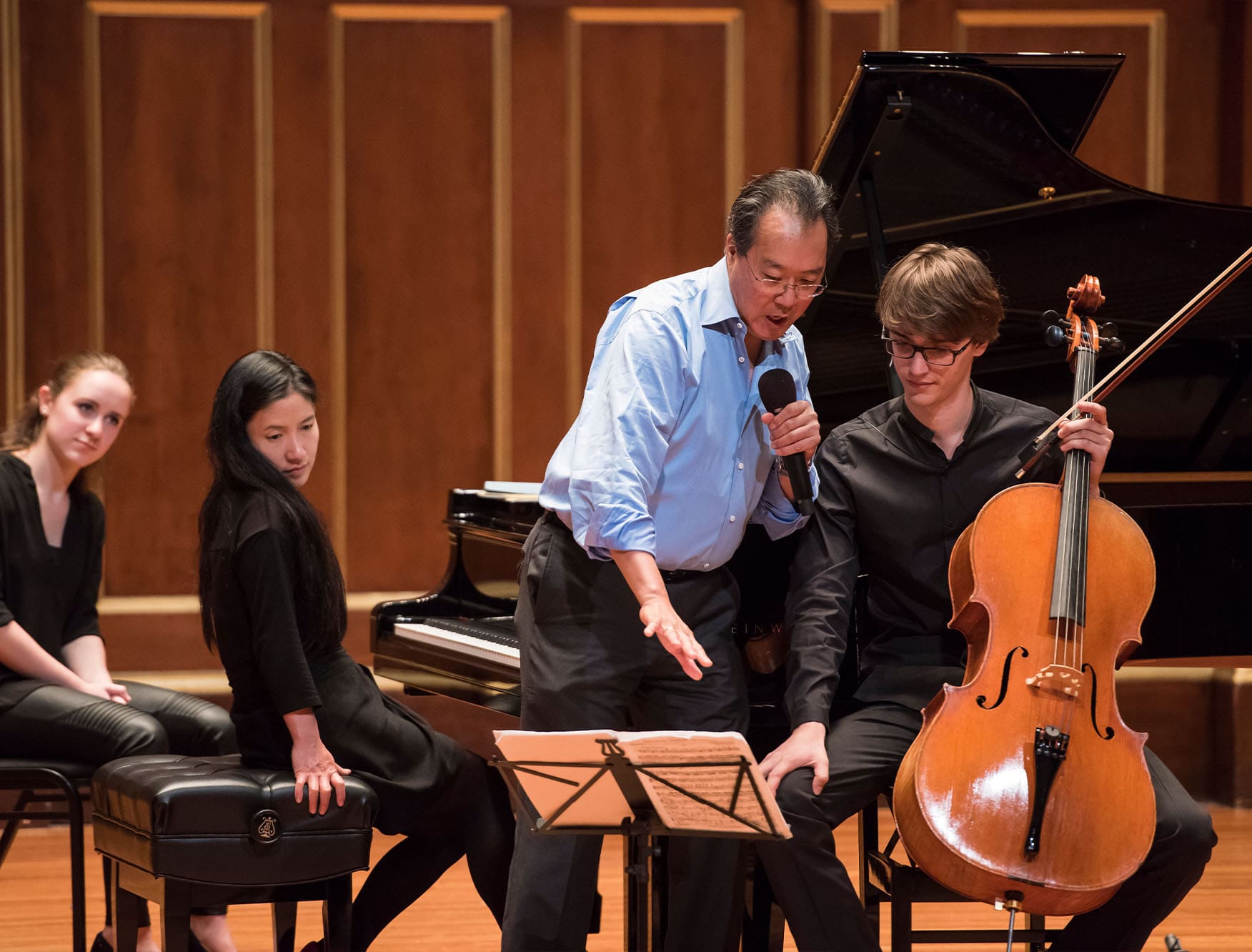 A teacher instructing three students with their instruments on the Jordan Hall stage.