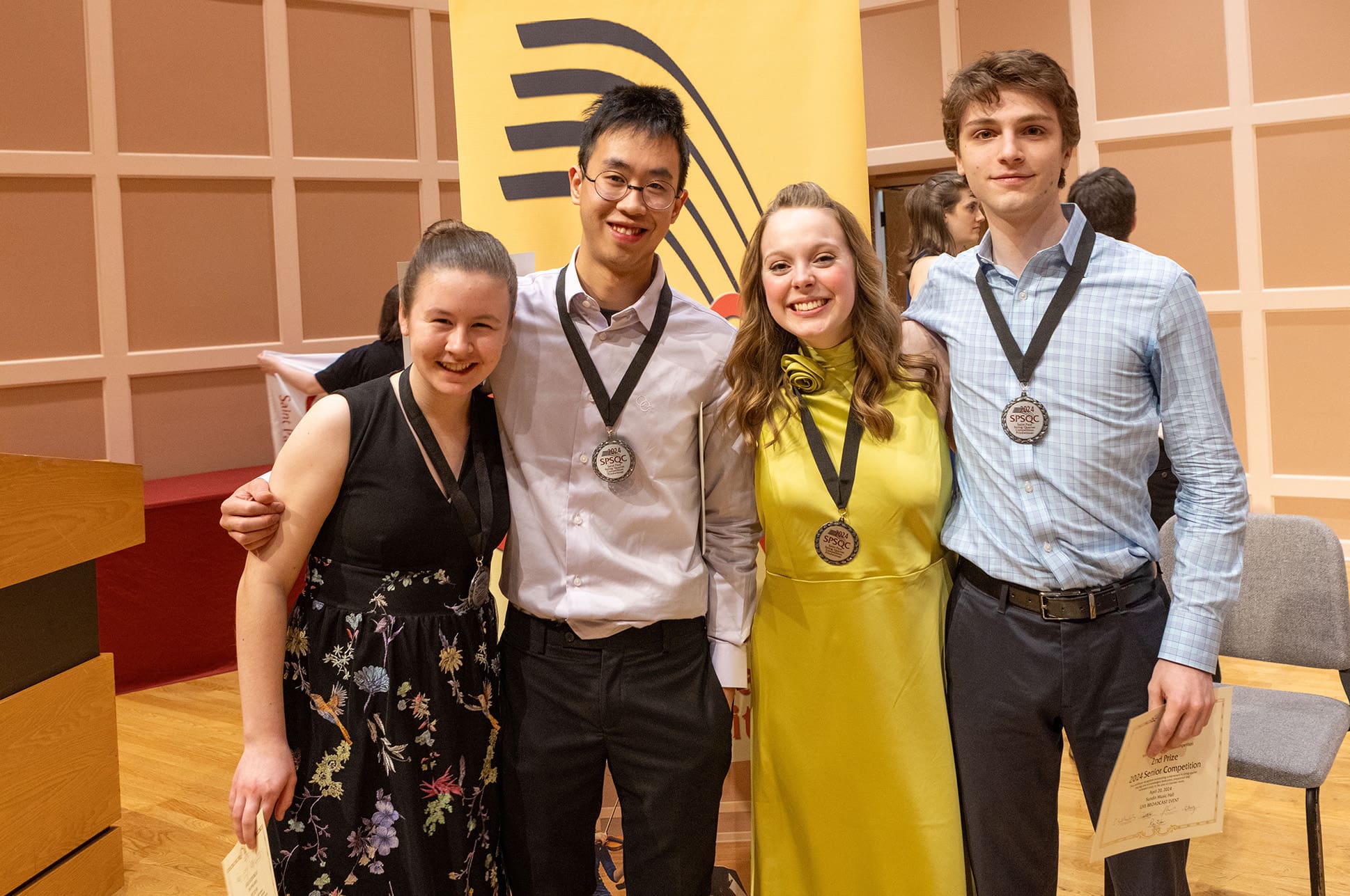 Four students wearing medals after receiving an award.