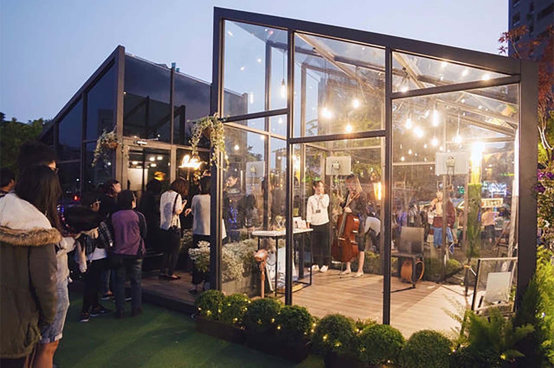 Gathering of students in a glass house outdoors for an event.
