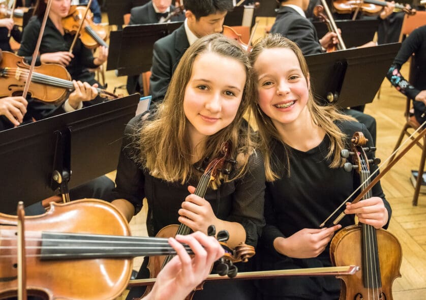 Two young students pose with their violins