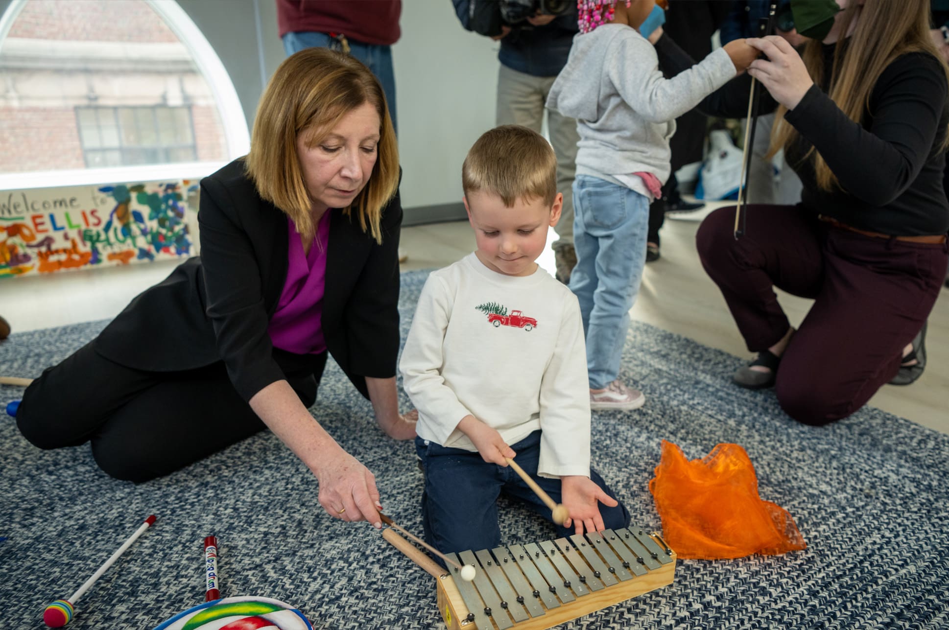 NEC President Andrea Kalyn and a child playing a mallet instrument.