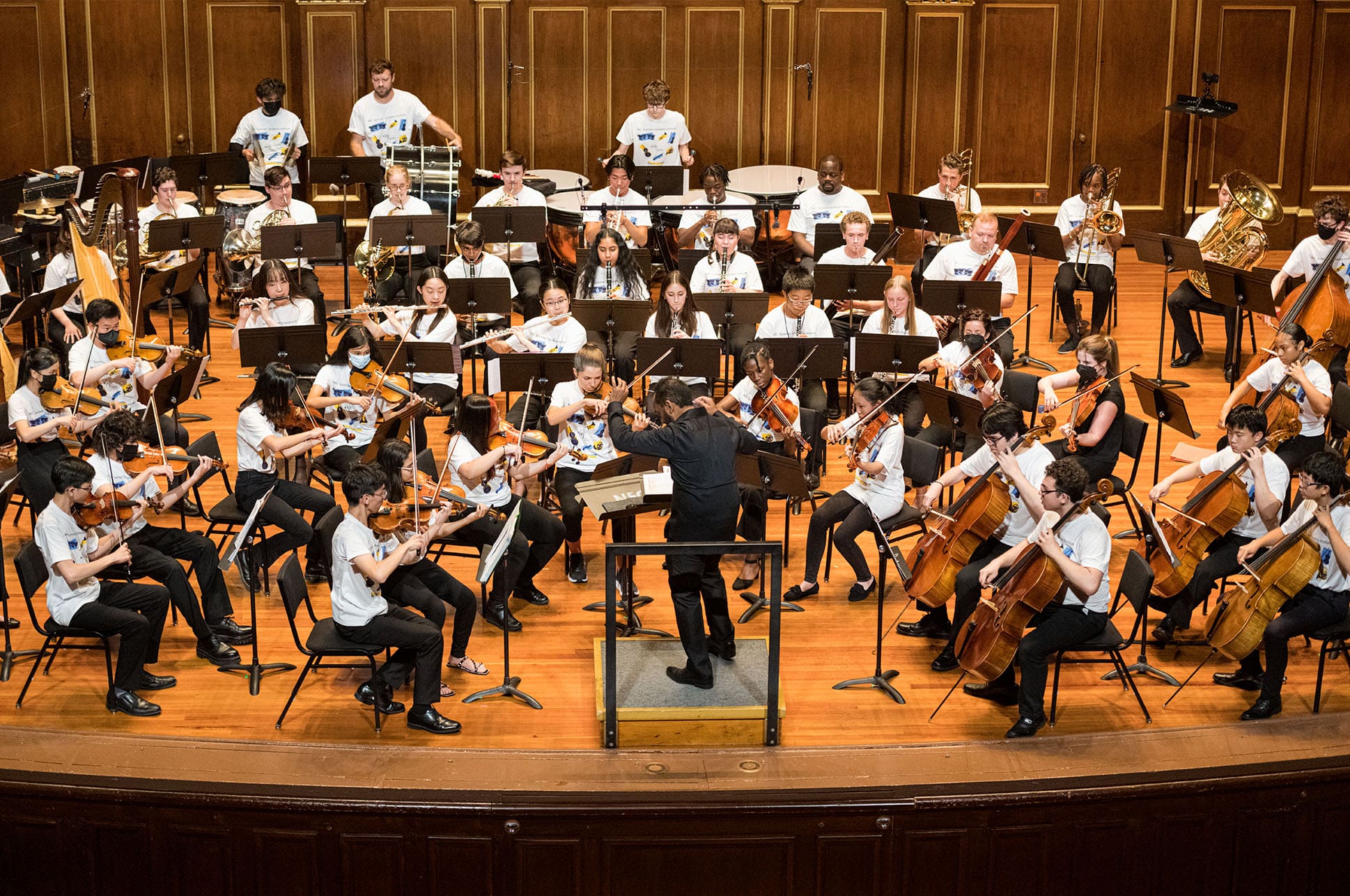 Students playing in an orchestra on the Jordan Hall stage.
