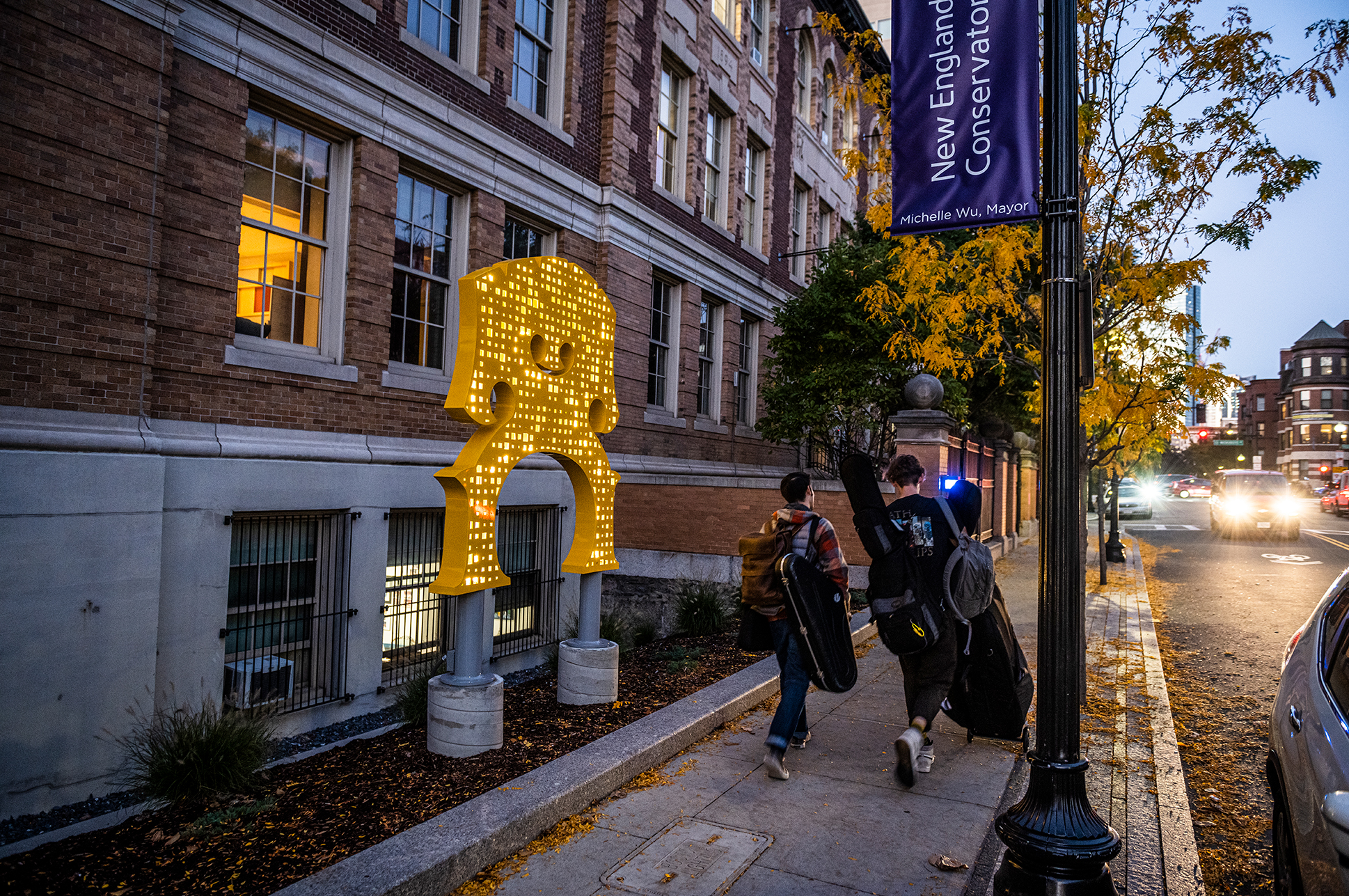 Exterior photo of NEC's building on St. Botolph Street with two students walking down the sidewalk.