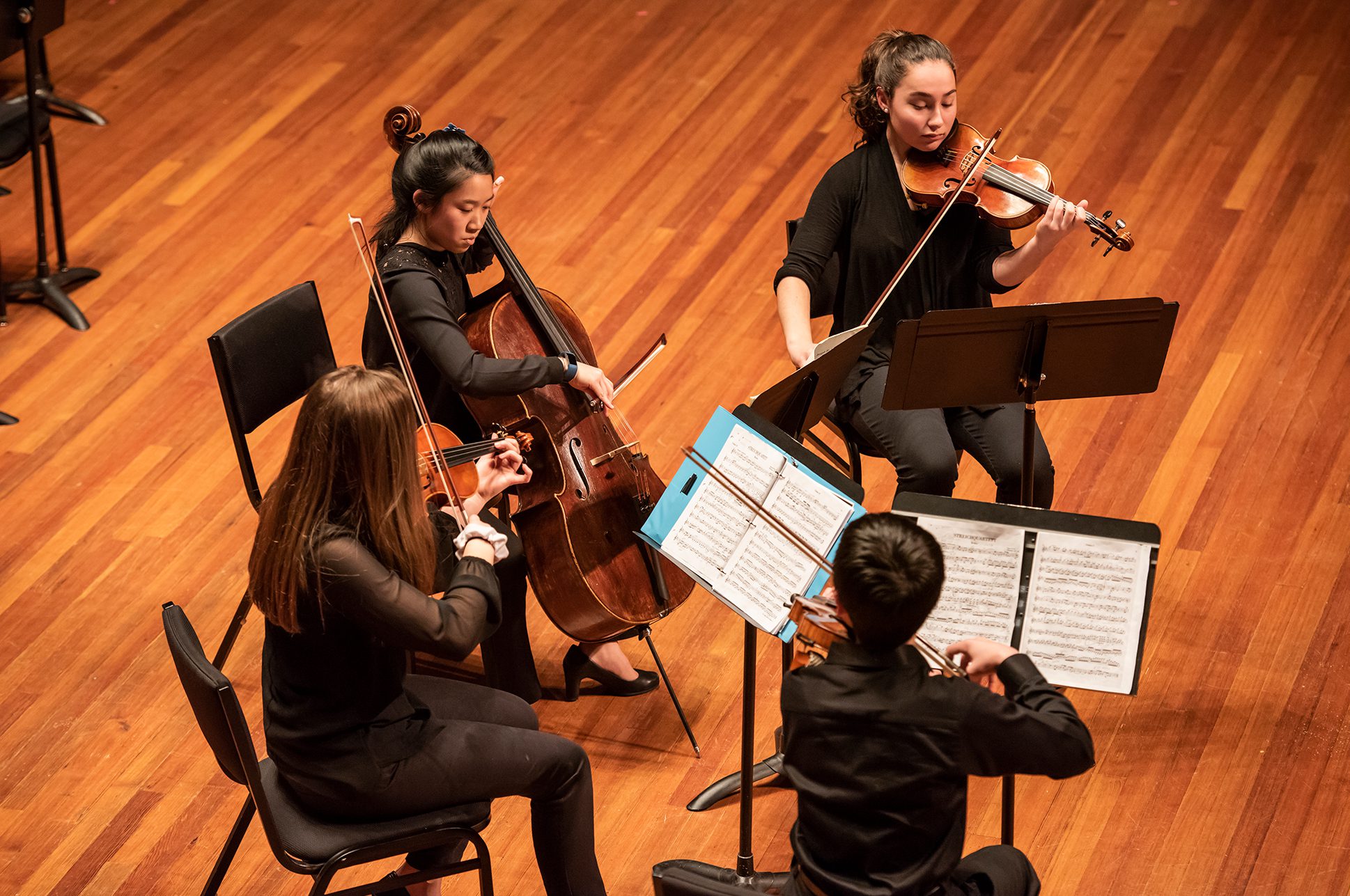 Four students playing in a chamber music quartet on the Jordan Hall stage.