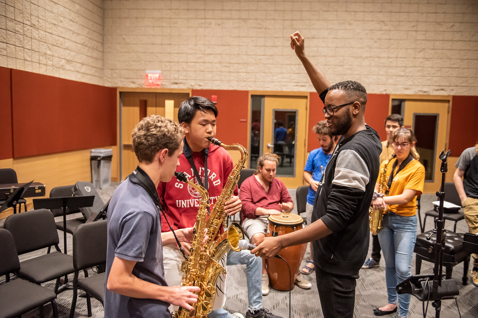 Two young students playing brass instruments guided by a music teacher.