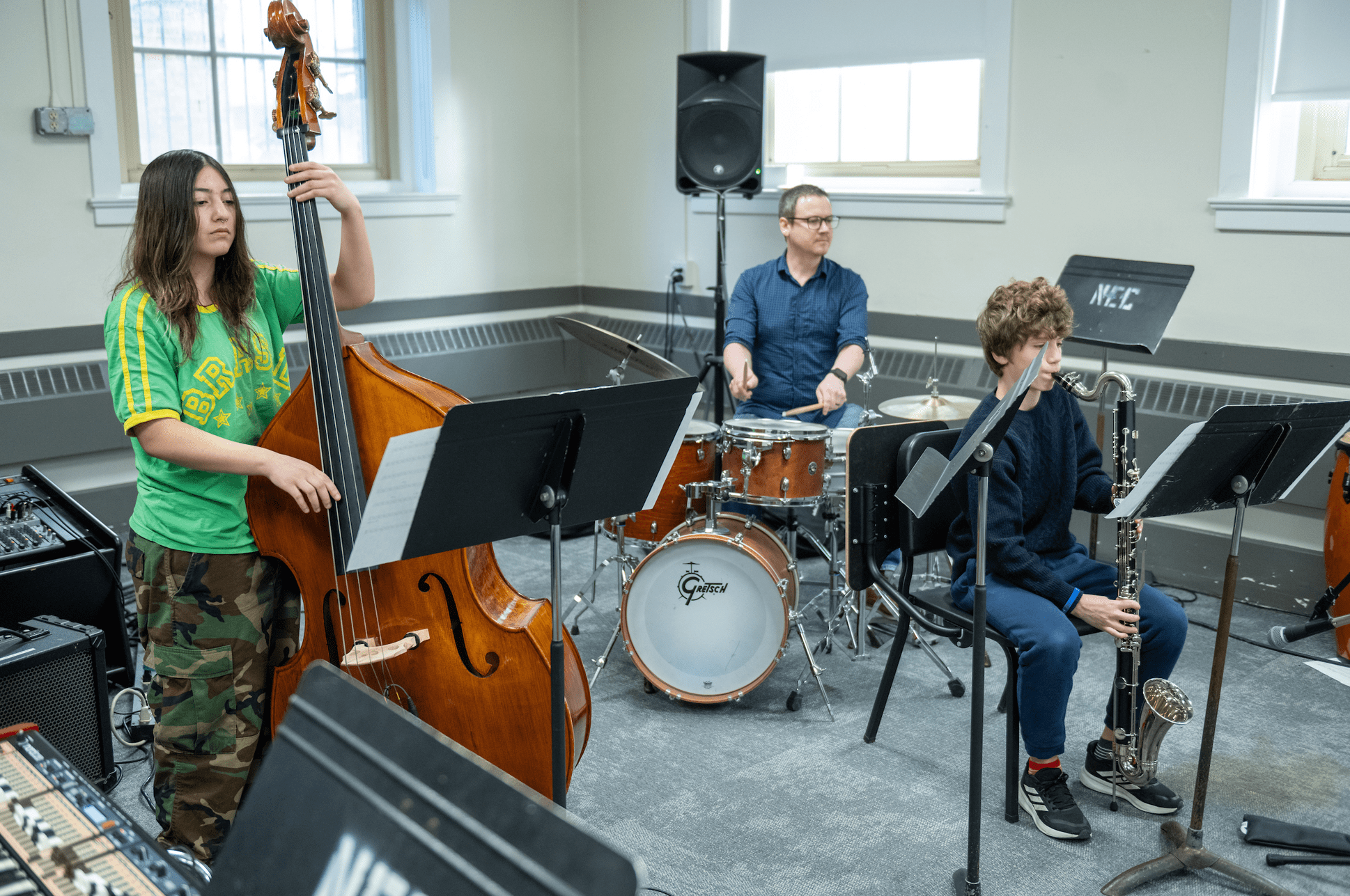 Prep-Info-Session-Jazz Two young students playing bass and saxophone in a jazz trio with a teacher on drums.