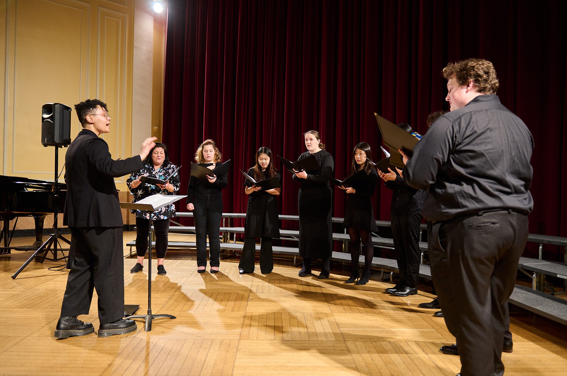 A small choir singing, led by a conductor.