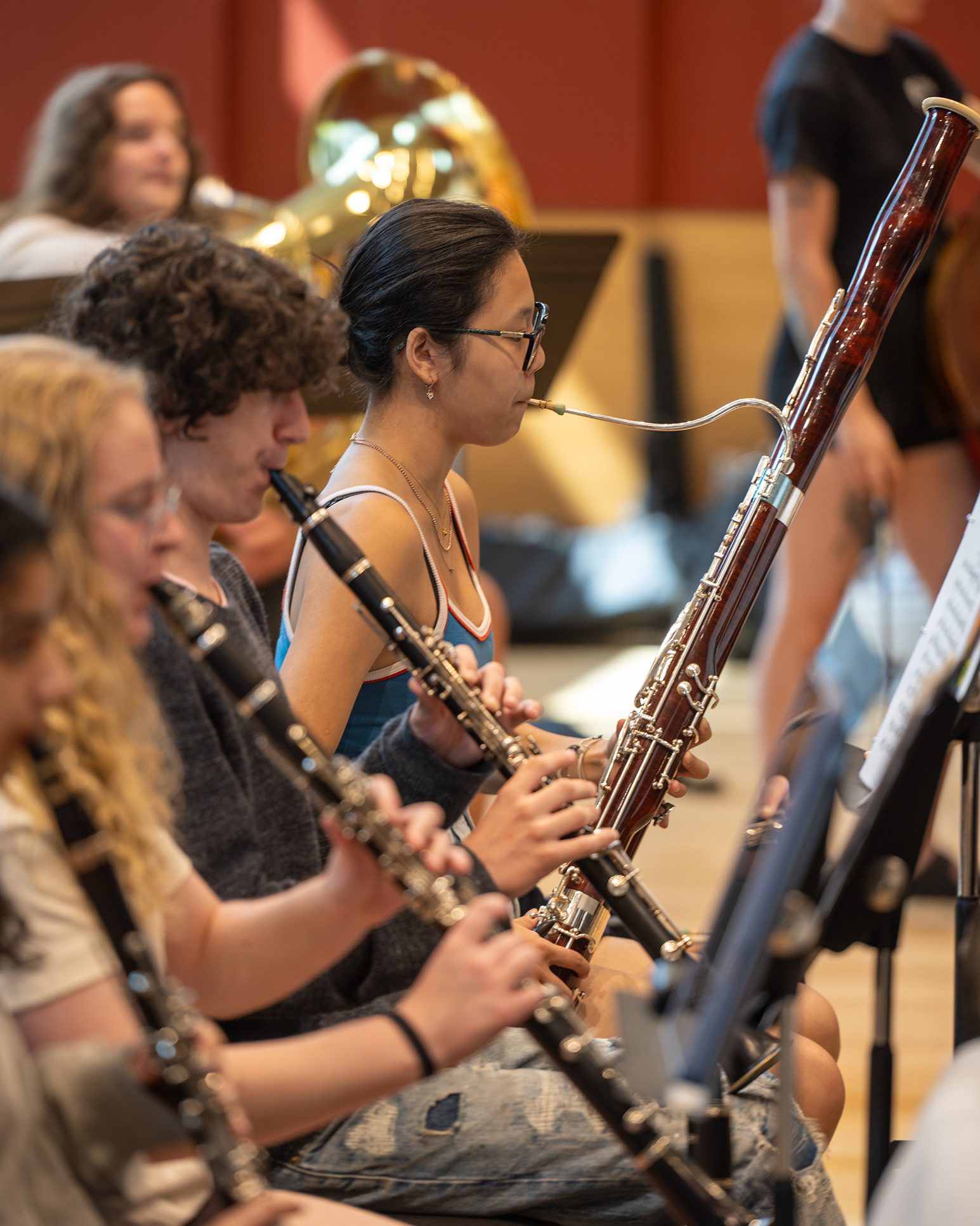 Students playing wind instruments in an orchestra rehearsal.