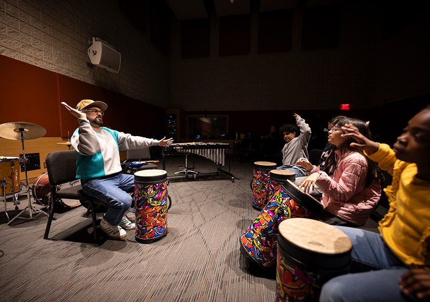 Young students and a teacher in a drumming class.