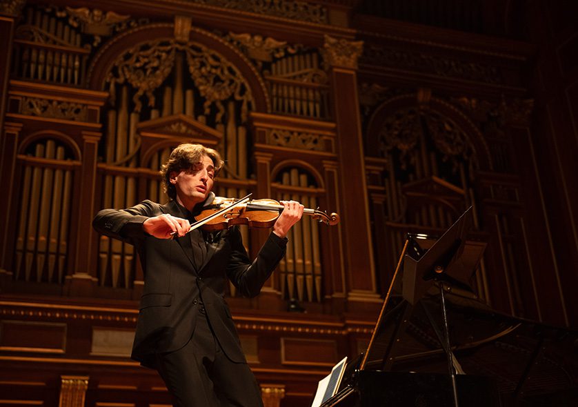 Joshua Brown playing violin on the Jordan Hall stage.