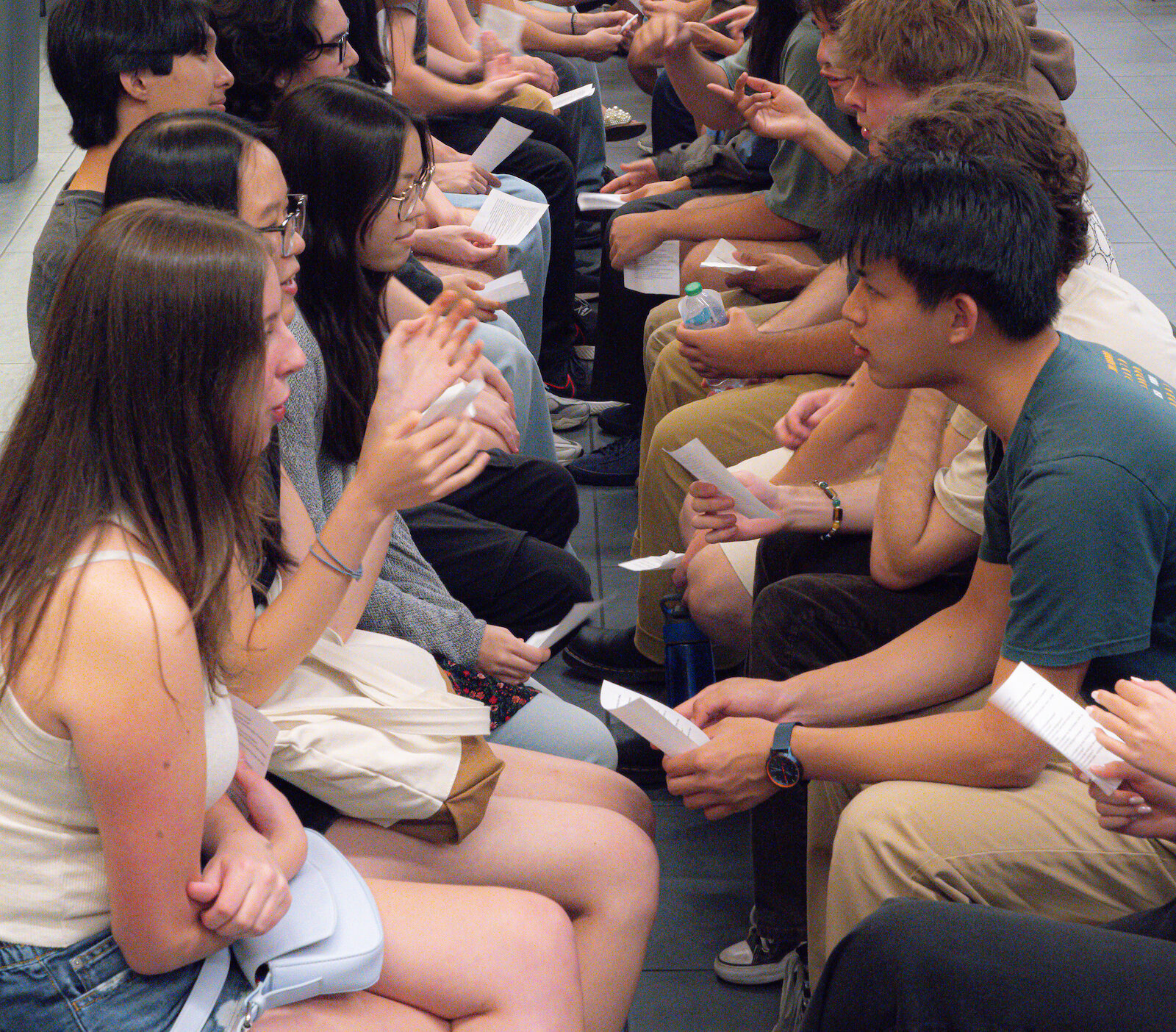Students sitting in a line participating in an orientation activity.