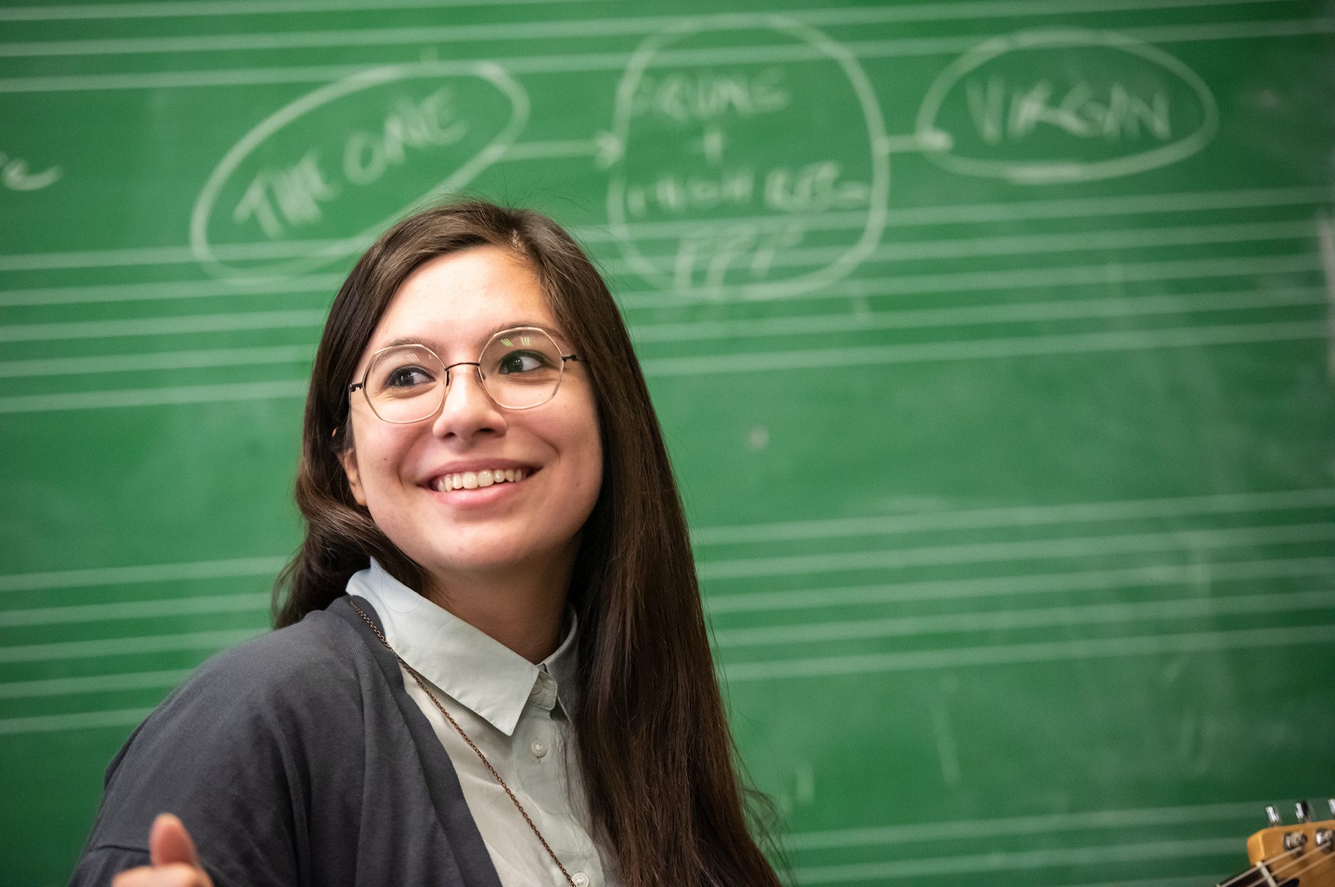 Student smiling in front of a chalkboard.