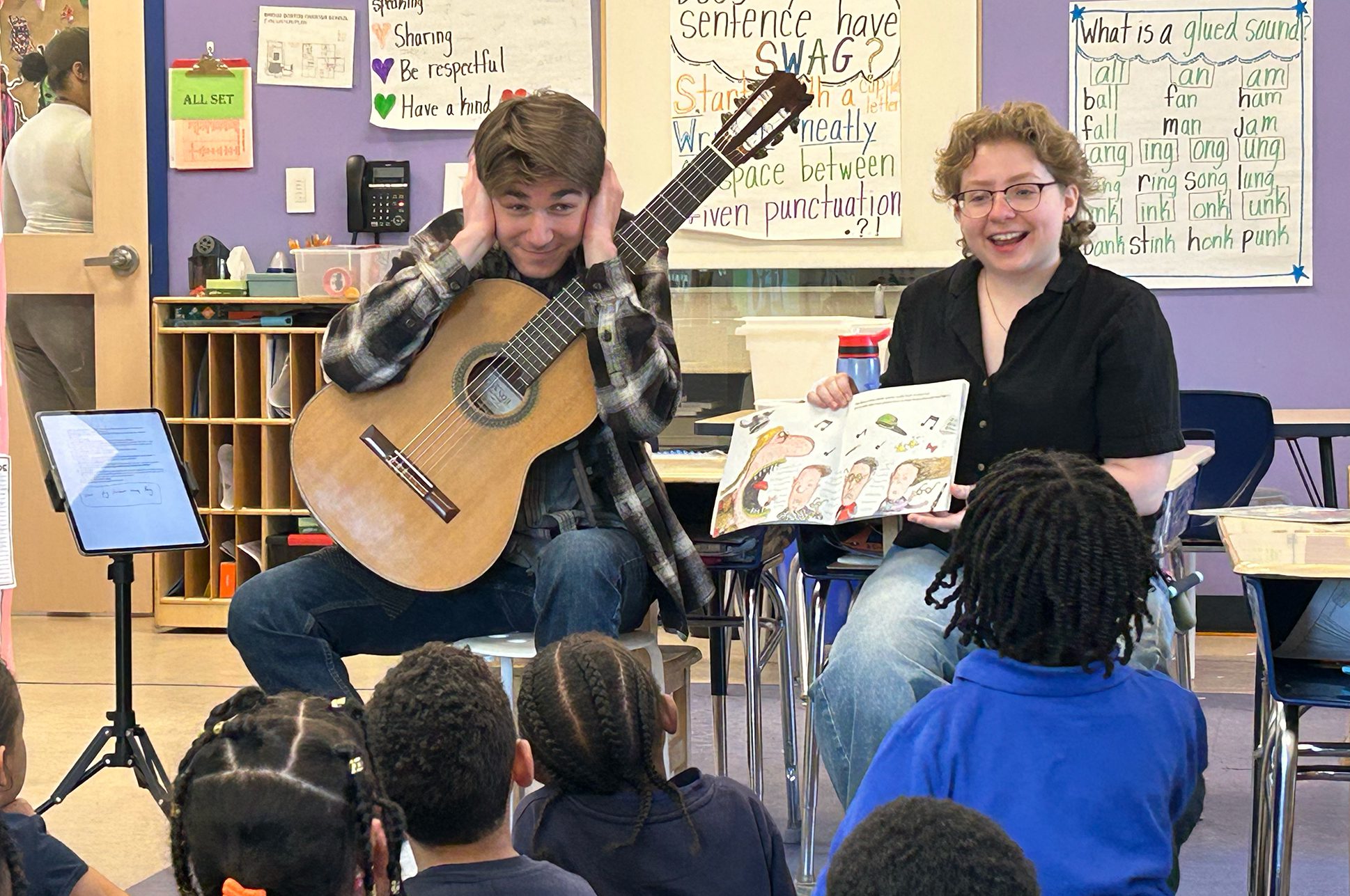 Two musicians teaching a class of young children in a classroom. Two musicians teaching a class of young children in a classroom.