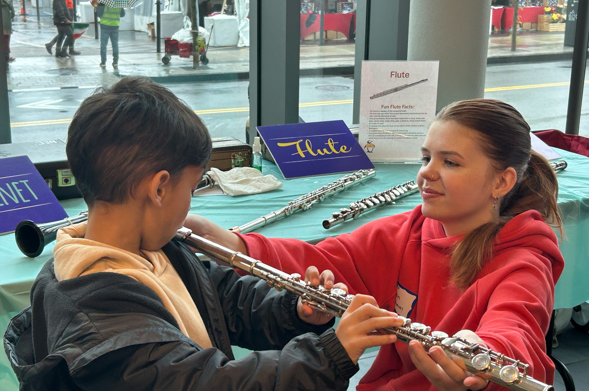 A young teacher helping a child play the flute.