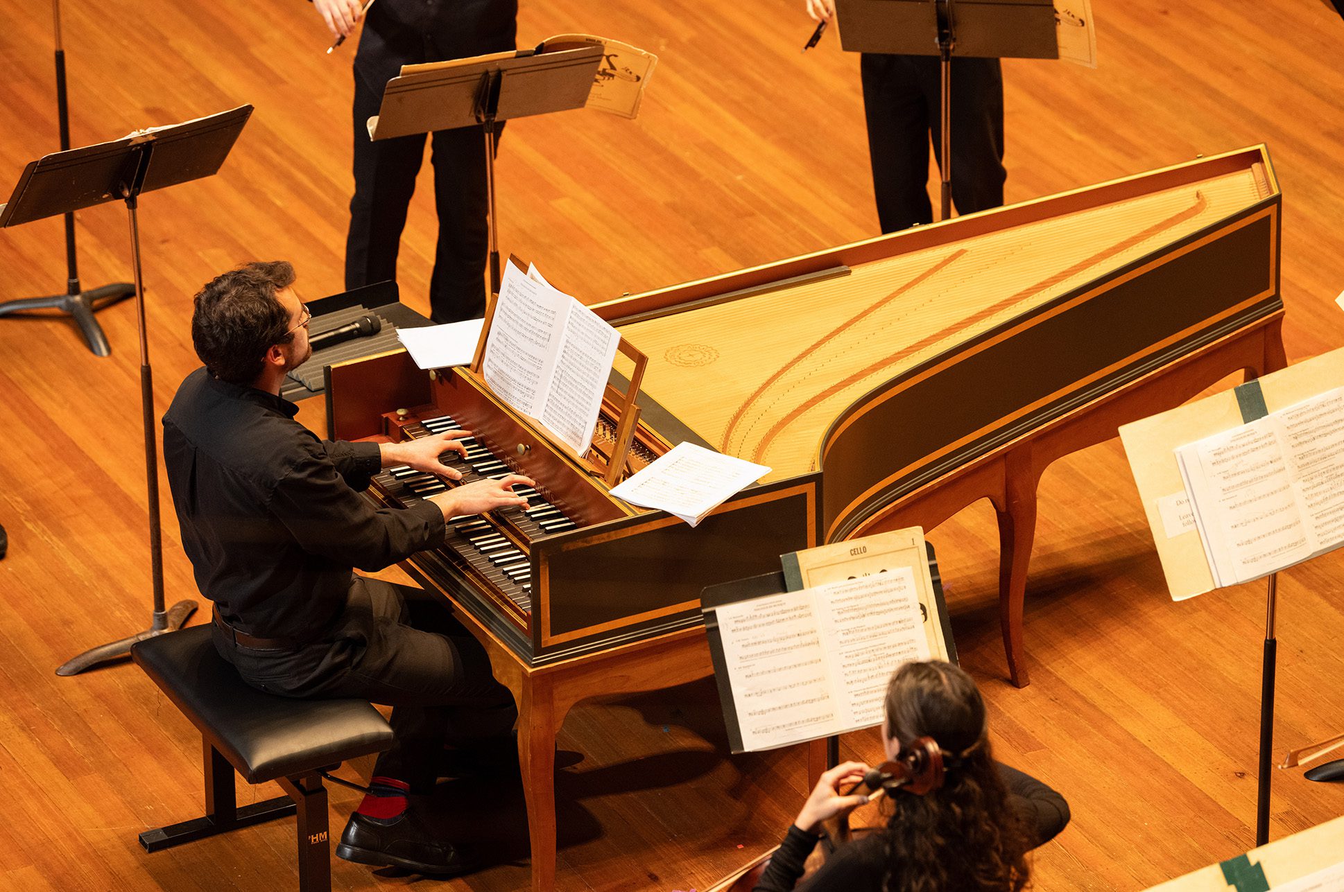 Person playing a harpsichord on stage. Person playing a harpsichord on stage.